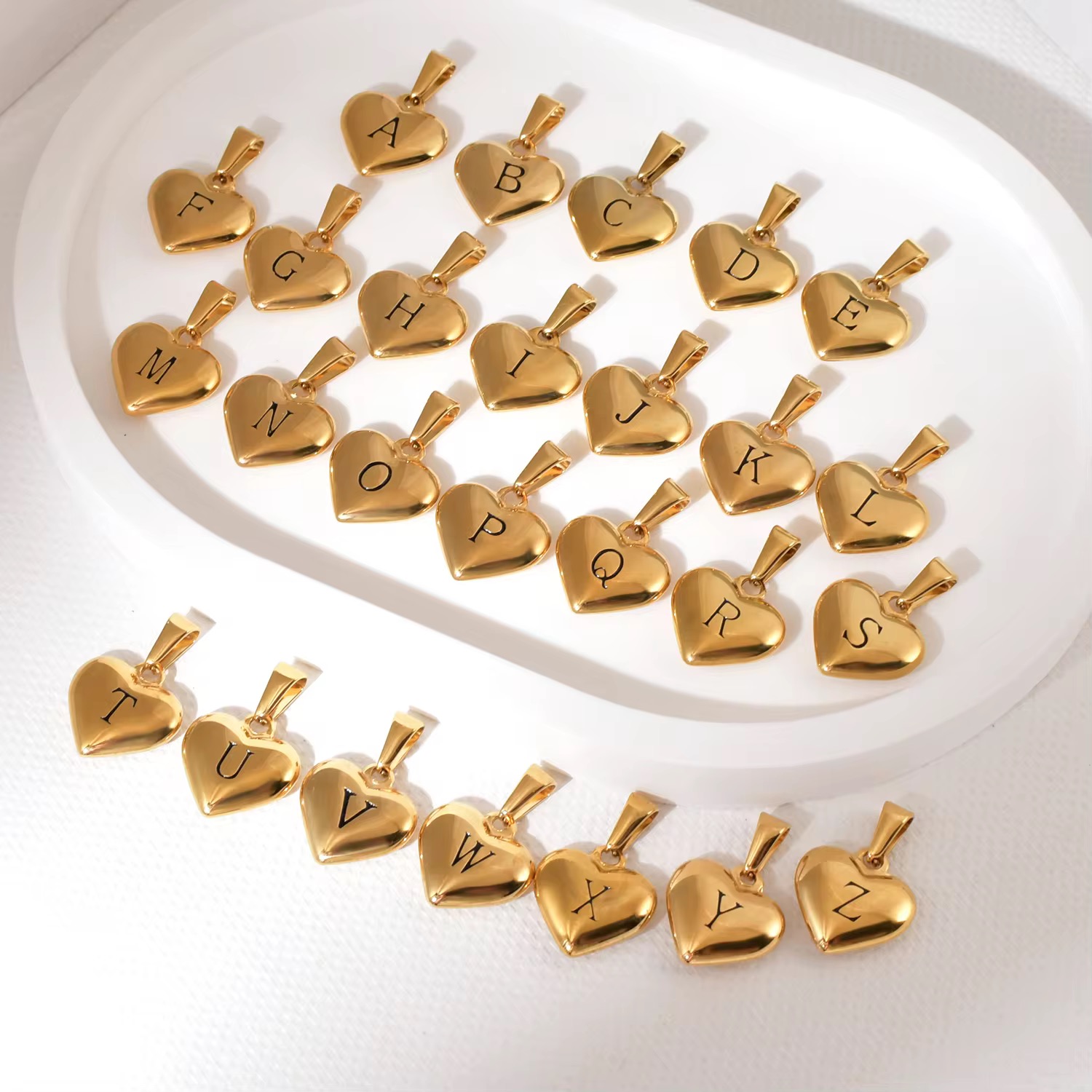 Stainless steel pendant plated with 18K gold in the shape of letters.