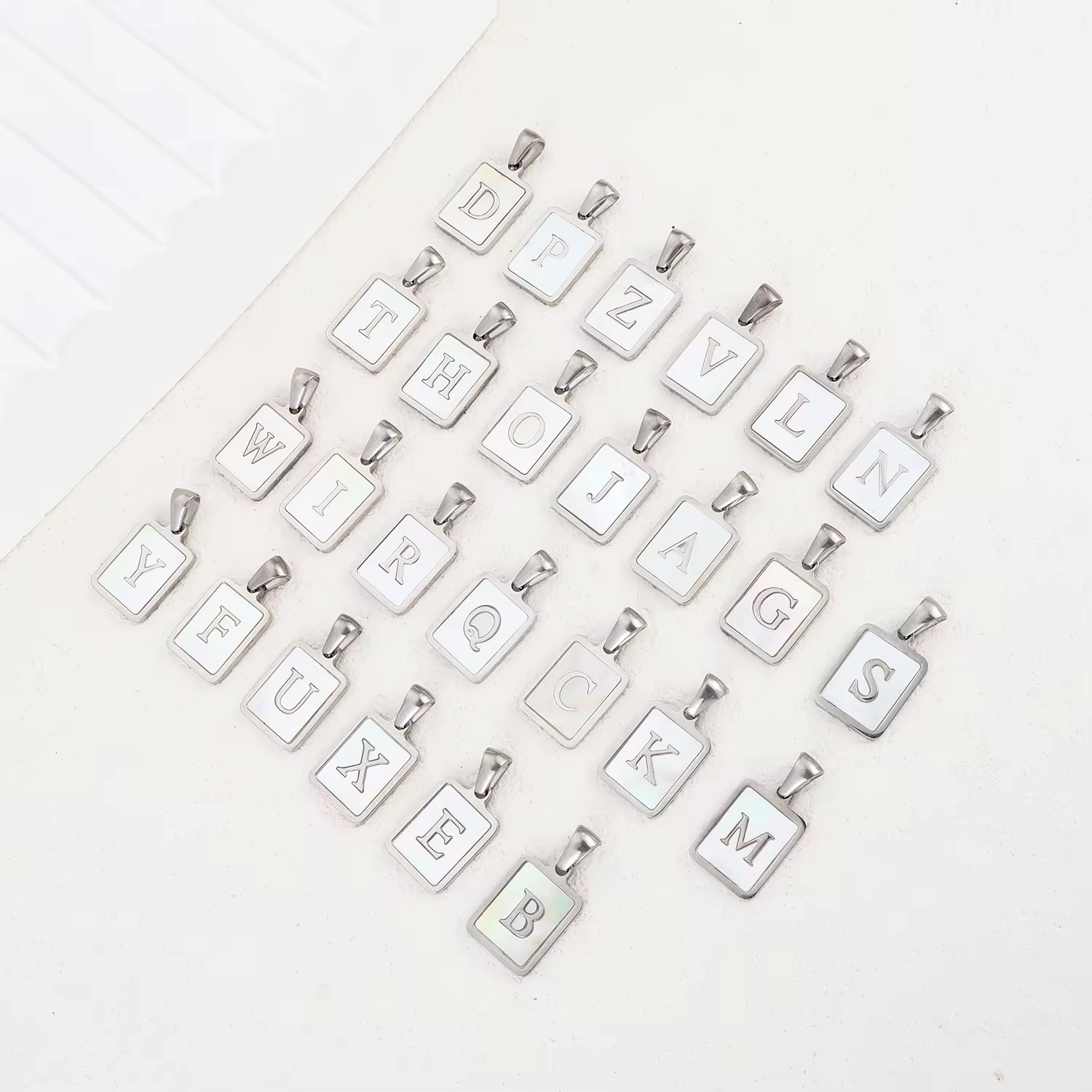 Stainless steel pendant plated with 18K gold in the shape of letters.